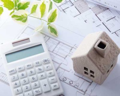 A calculator, a model of a home, and architectural drawings.
