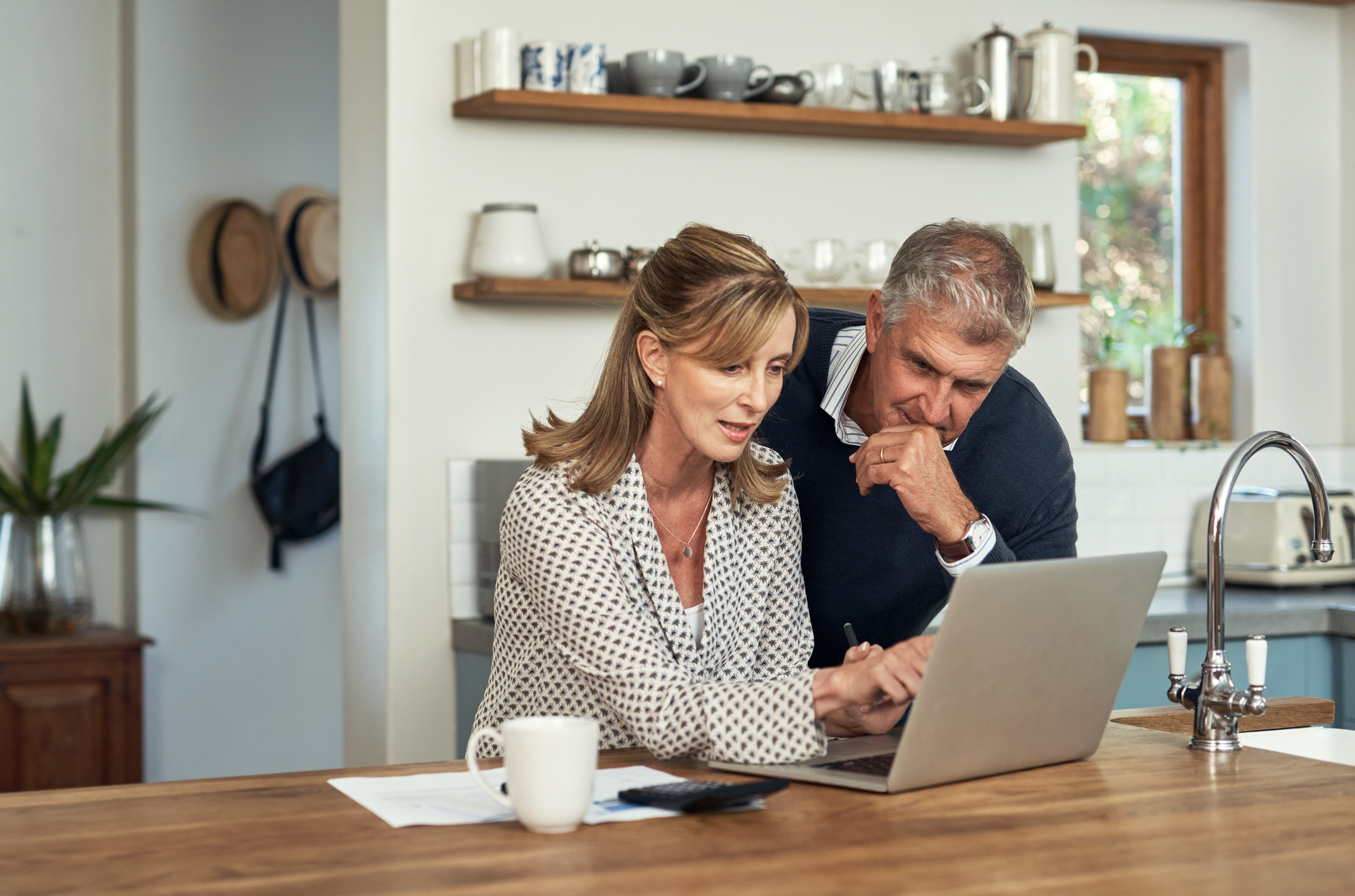 A senior couple planning their finance and paying bills while using a laptop at home. A mature man and woman going through paperwork and working online with a computer | How Long Does It Take to Get a HELOC