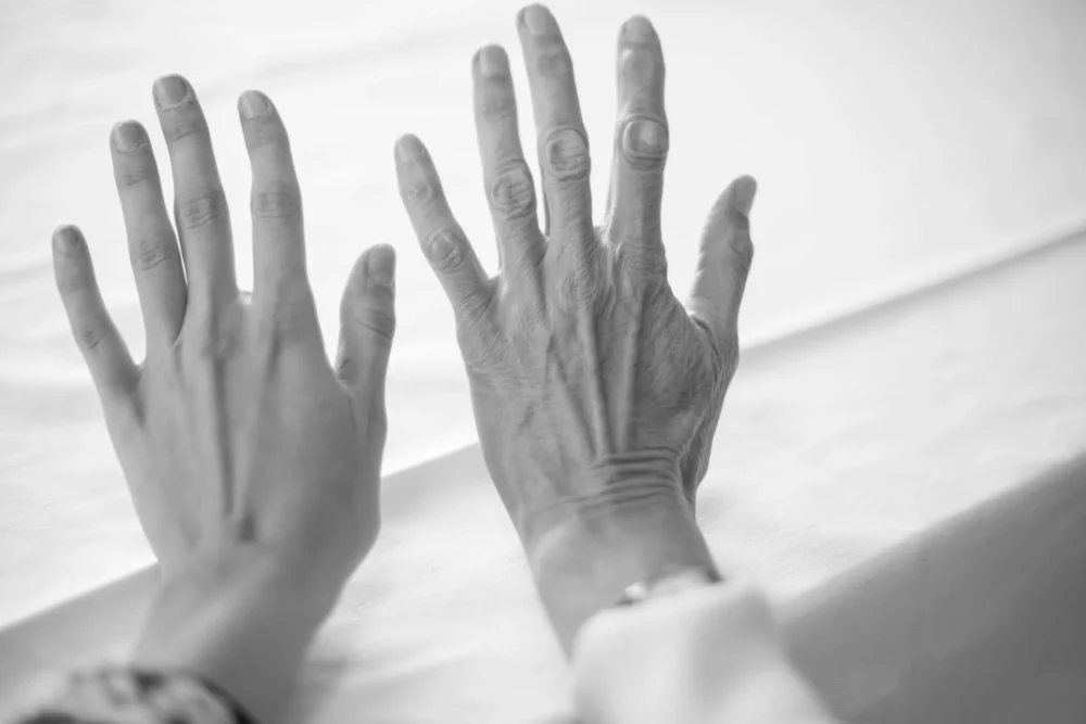 black and white photo of a young hand next to an old hand
