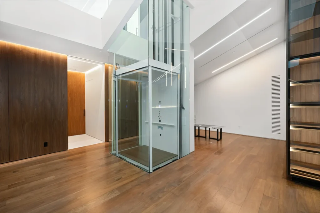 an-empty-room-with-wood-floors-and-a-glass-elevato